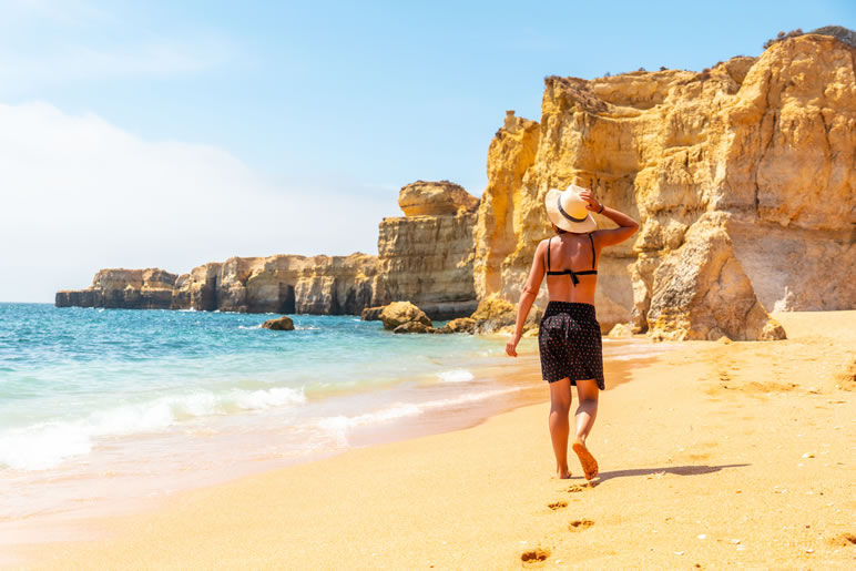 img blog a woman with a hat on a beach holiday at praia da 2022 08 30 20 17 14 utc
